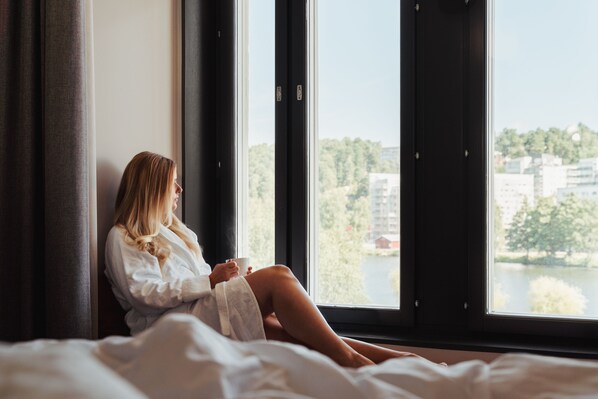 Una persona sentada junto a una ventana con vistas a edificios y árboles.
