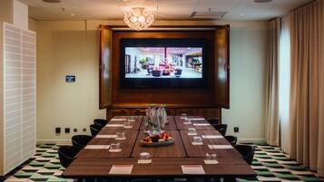 A conference room with a large screen, a wooden table, and a patterned floor.