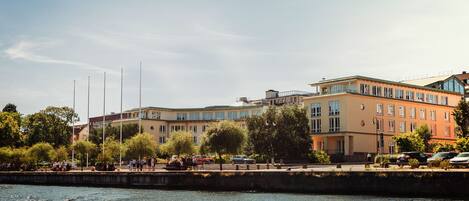 A waterfront building with multiple floors, large windows, and a flat roof.