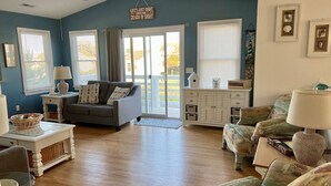 A spacious living room with a gray sofa, a patterned armchair, and a white cabinet. - Ocean + sound views | Soooo close to the beach! (Duck)