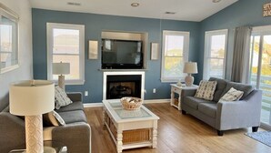 A living room with a fireplace, two sofas, a coffee table, and a television. - Ocean + sound views | Soooo close to the beach! (Duck)