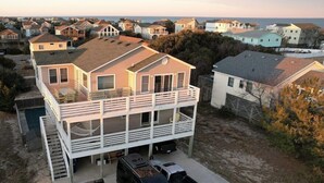 A two-story house with a balcony, a garage, and a driveway with two vehicles. - Ocean + sound views | Soooo close to the beach! (Duck)