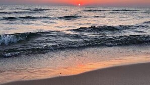 A beach with waves and a sunset in the background.