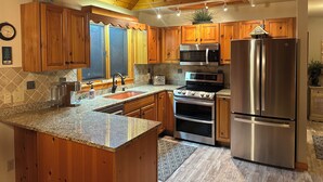 A kitchen with wooden cabinets, stainless steel appliances, granite countertops, and a window with a view.