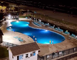 A swimming pool with lounge chairs and a lifeguard stand.