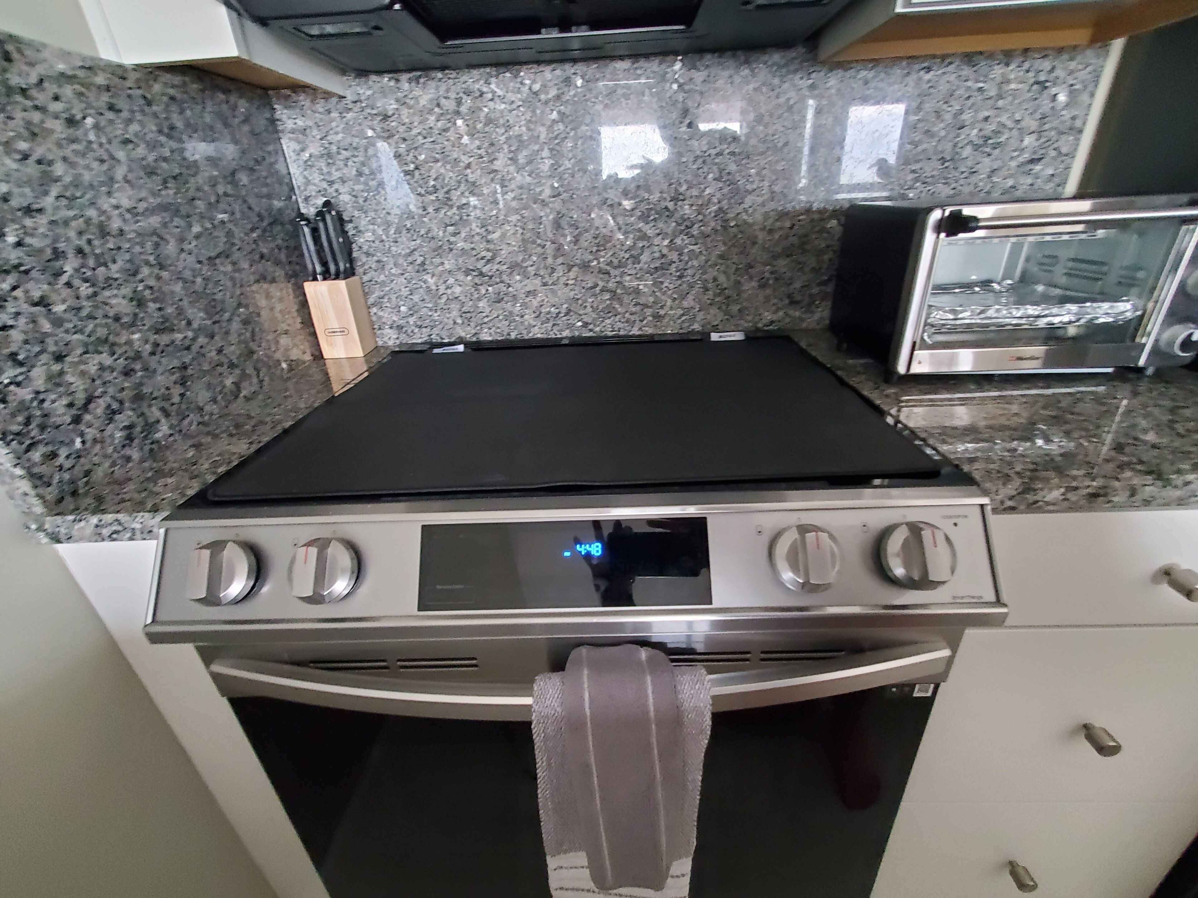 A kitchen with a stove, toaster, and granite countertop.