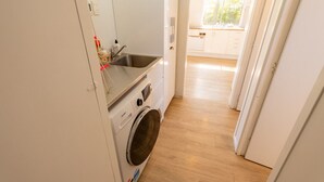 A compact kitchen with a washing machine, a sink, and a window.