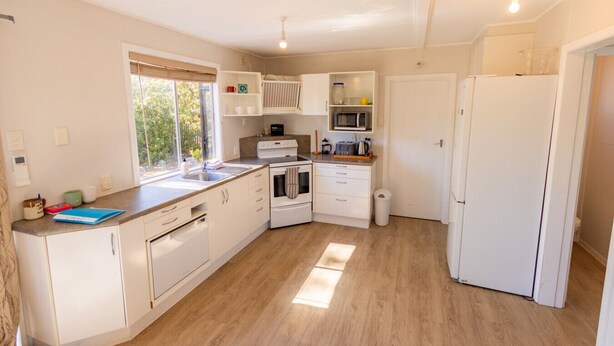 A modern kitchen with white cabinetry, a built-in oven, a microwave, and a sink.