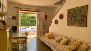A cozy living room with a sofa, a dining table with chairs, a TV, and a painting on the wall. - La Casa di Paola - Four Bedroom Apartment, Sleeps 8 (Panoramica)