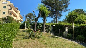A residential area with a building featuring balconies and a well-maintained garden with trees and shrubs. - La Casa di Paola - Four Bedroom Apartment, Sleeps 8 (Panoramica)