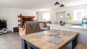 A modern living room with a wooden table, a brick fireplace, a sofa, and a TV.