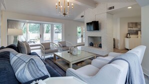 A spacious living room with a glass coffee table, white sofas, and a fireplace. - 9 Baynard Cove Road at The Sea Pines Resort (Hilton Head Island)