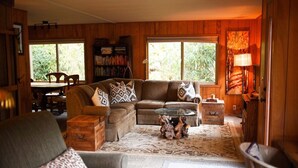 A cozy living room with a sectional sofa, a coffee table, and a bookshelf.