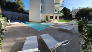 A modern building with a swimming pool, outdoor seating, and a balcony. - Sunny apartment 1B with balcony & pool in canyamel (Capdepera)