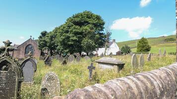 A cemetery with gravestones, a church, and a large tree.
