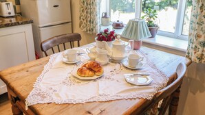 Et spisebord dækket med et blondeborddug, te, kopper, underkopper og en tallerken med croissanter.