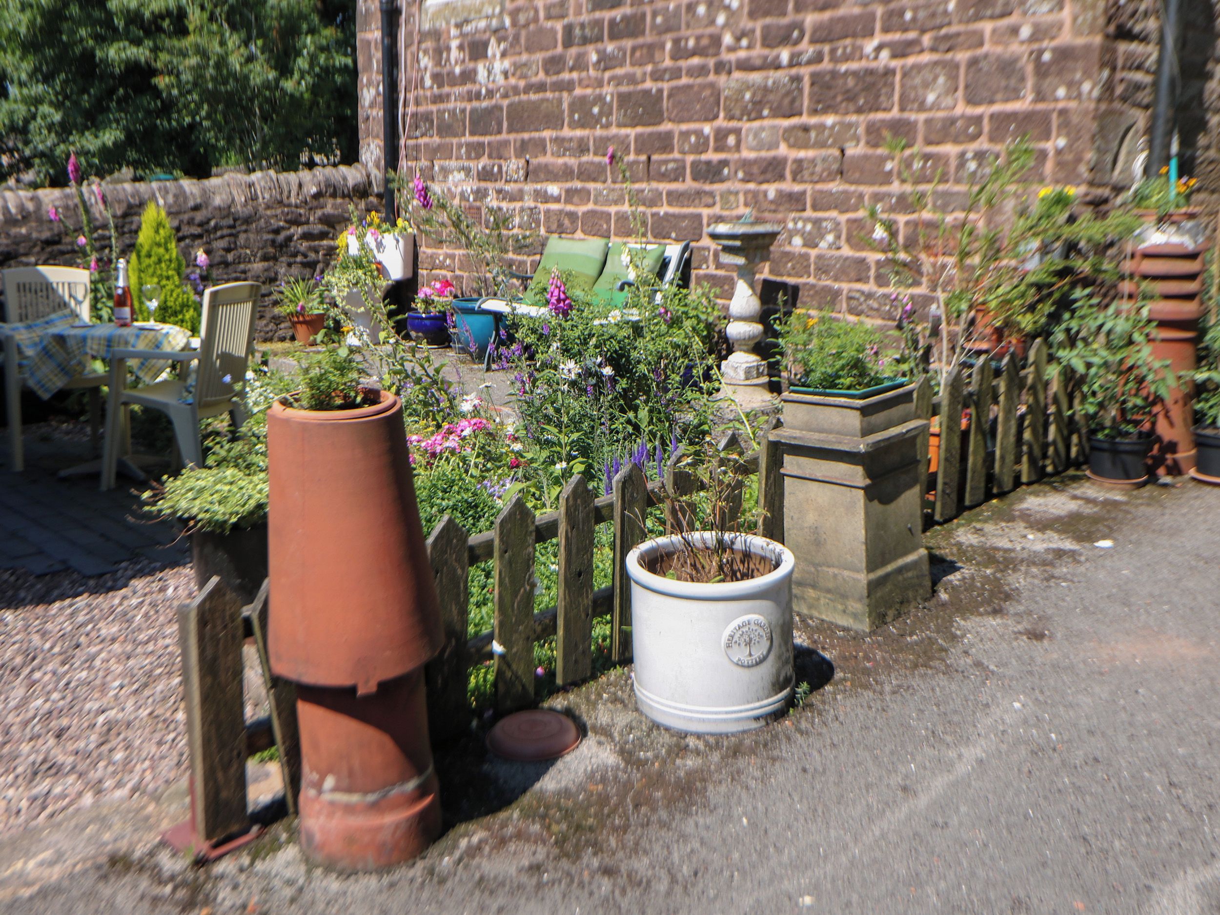 A garden with potted plants, a brick wall, and a wooden fence.