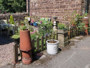 Ein Garten mit Kübelpflanzen, einer Backsteinmauer und einem Holzzaun.