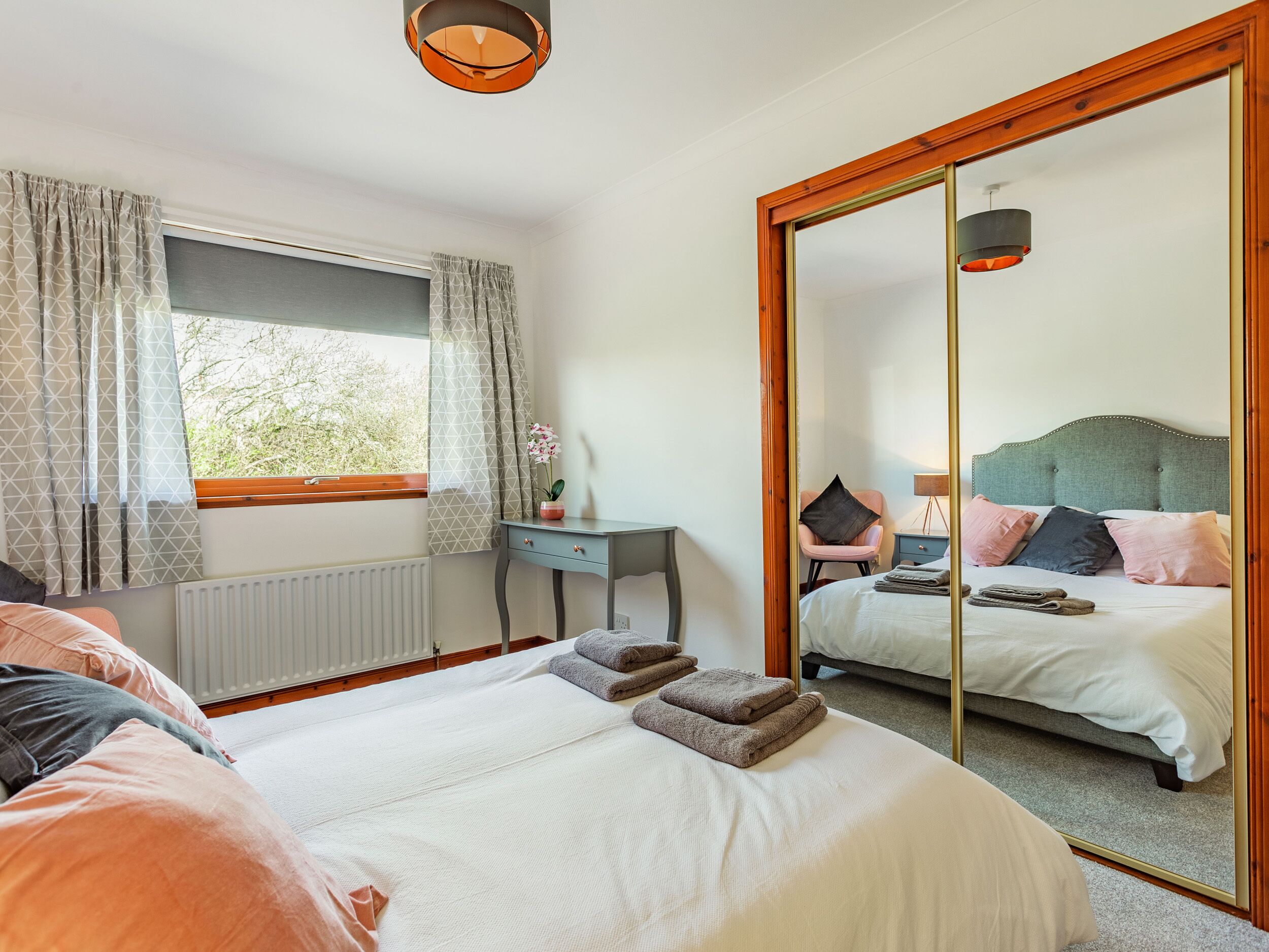 A bedroom with a large bed, a desk, a chair, and a mirror.