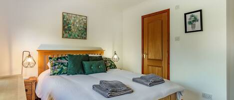 A neatly made bed with pillows, a bedside lamp, and a wall-mounted artwork.