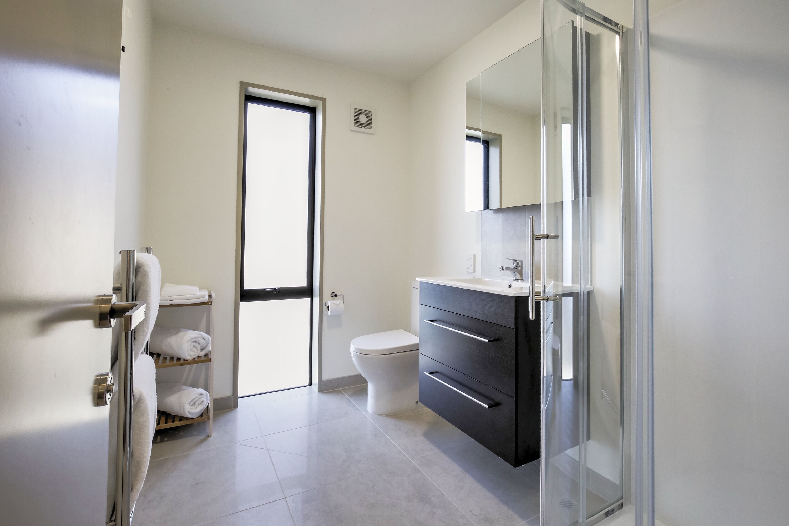 Un baño moderno con inodoro, tocador con espejo y cabina de ducha de vidrio.