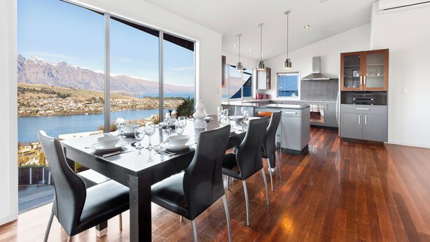 A modern kitchen with a large island, a dining area with a view of a lake and mountains, and a spacious living area.
