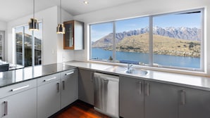 A modern kitchen with stainless steel appliances, a large window with a mountain view, and a clean, minimalist design.