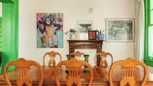 Un coin repas avec une table et des chaises en bois, une console décorative agrémentée de vases et des œuvres d’art murales.