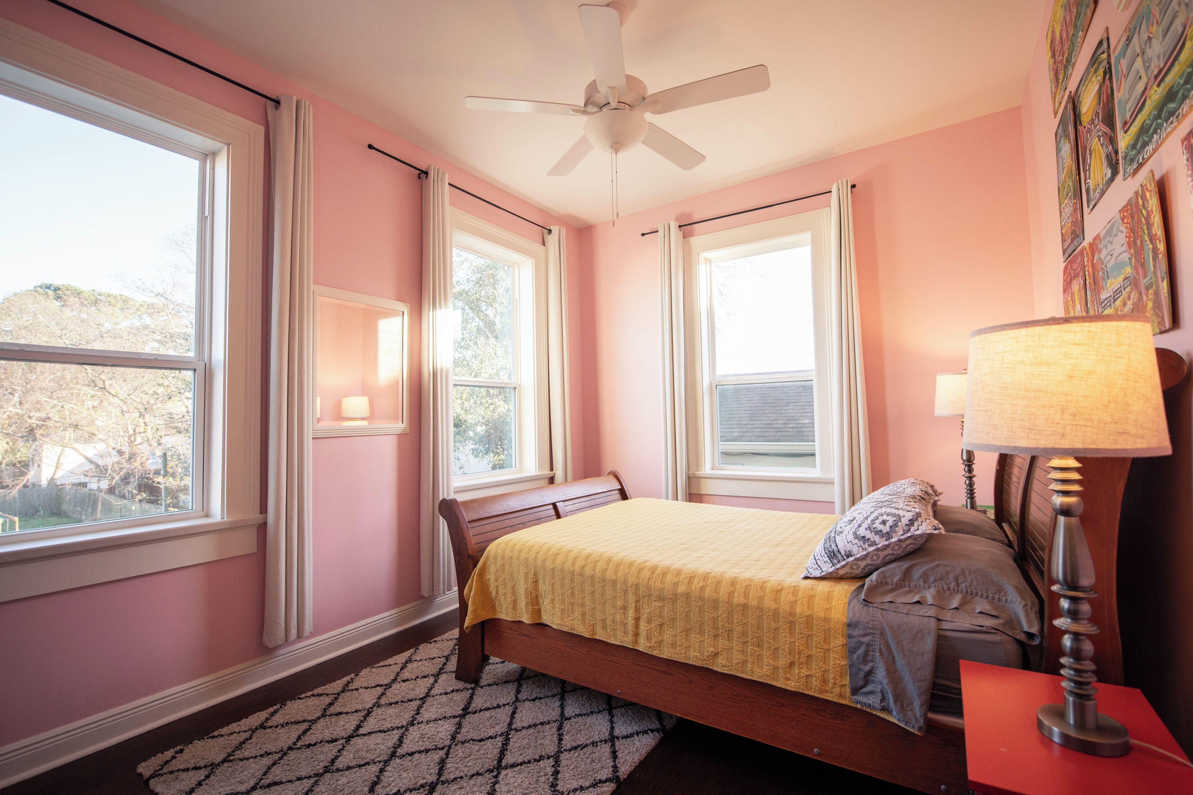 Un dormitorio con cama, ventilador de techo y ventanas.