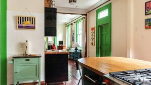 Une cuisine avec une table en bois, un poêle et une porte verte.