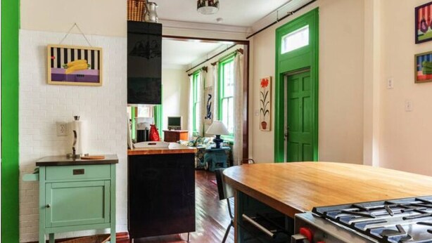 A kitchen with a wooden table, a stove, and a green door. - Okra Inn: Beautifully Designed B&B, Full Buyout, Off-Street Parking, Huge Yard (New Orleans)