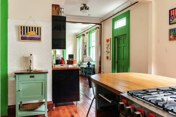 A kitchen with a wooden table, a stove, and a green door.