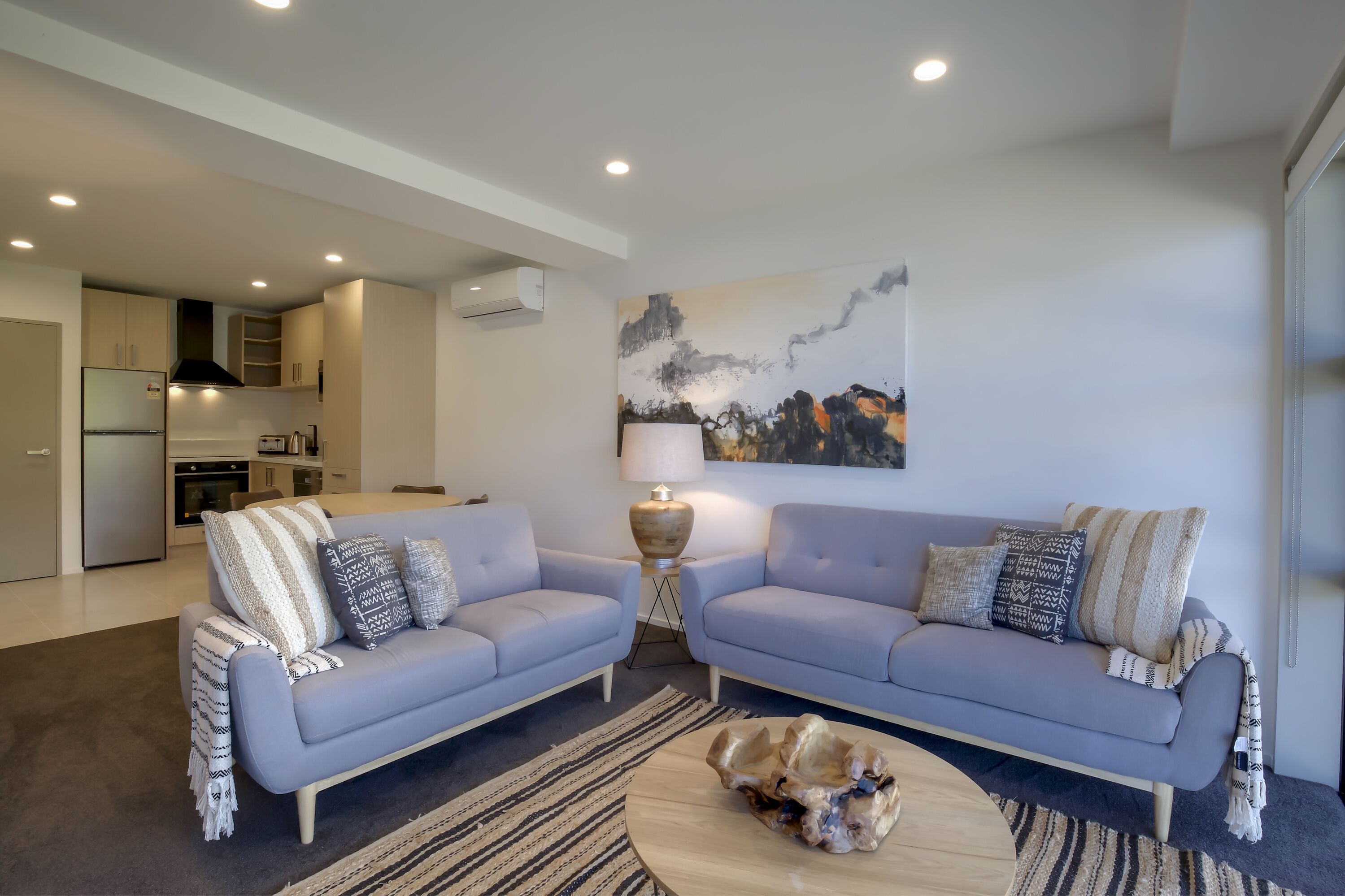 A modern living room with two sofas, a coffee table, and a painting on the wall.