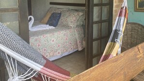A room with a bed, a hammock, and a view of the outside. - Recanto das Orquideas II (Quatis)