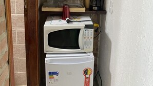 A compact kitchen with a microwave, a coffee maker, and a red pot on a shelf. - Recanto das Orquideas II (Quatis)
