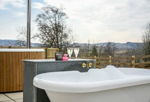 Un bain à remous avec une terrasse en bois et une vue sur les montagnes.