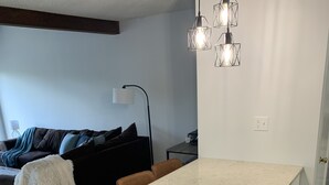 A modern kitchen with a central island, white cabinetry, and a hanging light fixture.