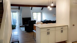 A modern kitchen with white cabinets, a wooden island, and pendant lighting.