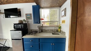 A compact kitchen with a refrigerator, microwave, stove, and sink. - Modern Cabin @ Moose Tracks Lodging (Kenai)