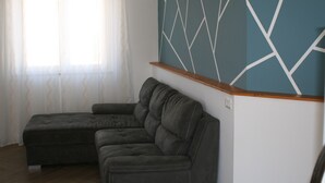 Uma sala de estar com um sofá seccional, um banco de madeira e uma parede com padrão geométrico.
