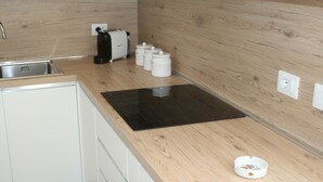 Uma cozinha com bancada de madeira, fogão por indução preto, torradeira e três recipientes brancos.