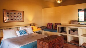 Une chambre à coucher comprenant un lit, une table de chevet, une commode, un banc et une étagère murale avec des paniers.