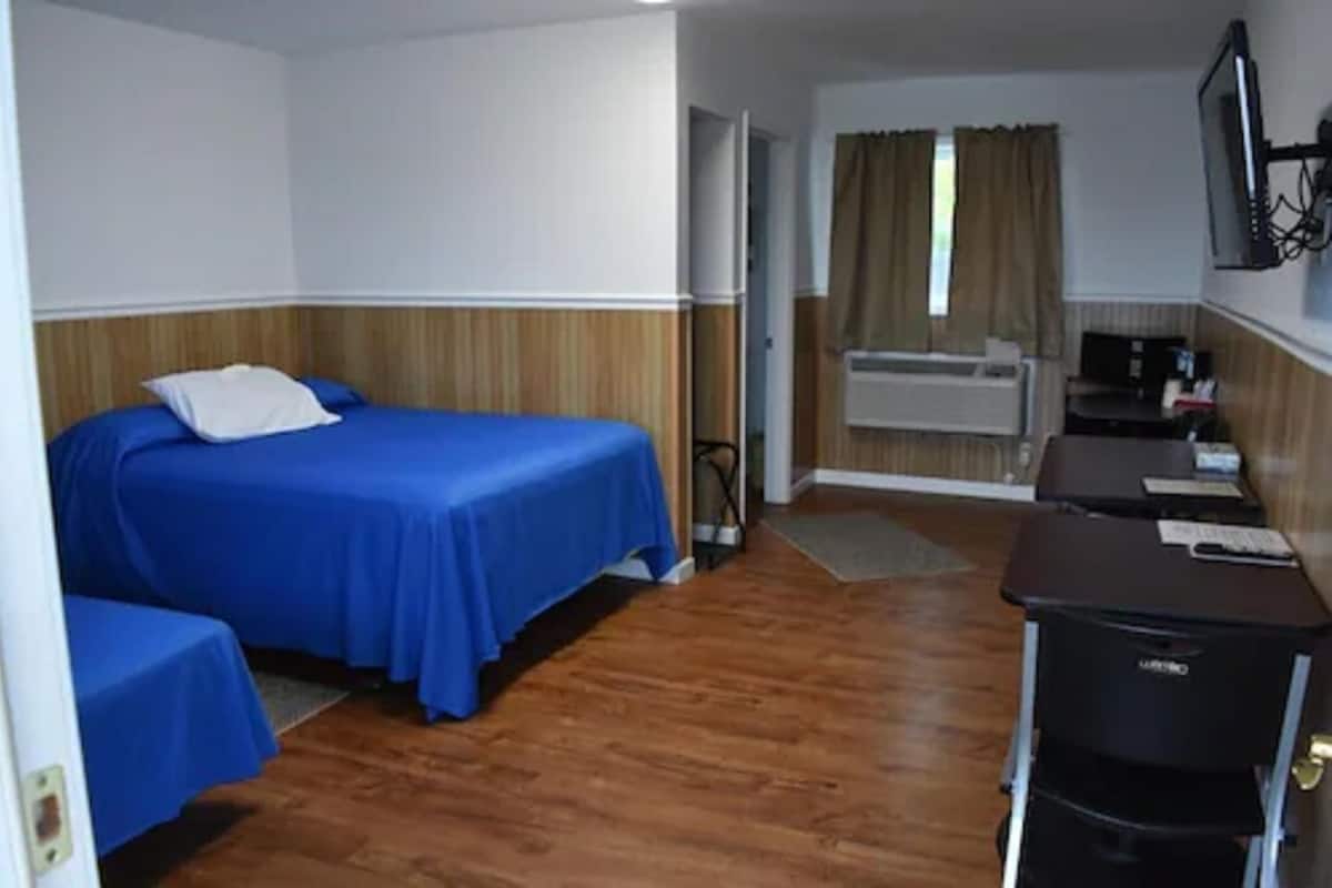A hotel room with a bed, a desk, and a small kitchenette.