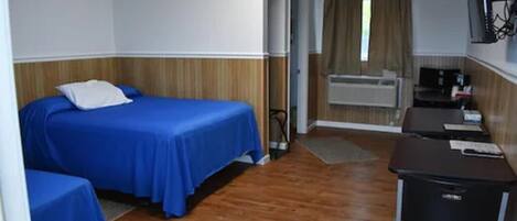 Una habitación de hotel con cama, escritorio y una pequeña kitchenette.