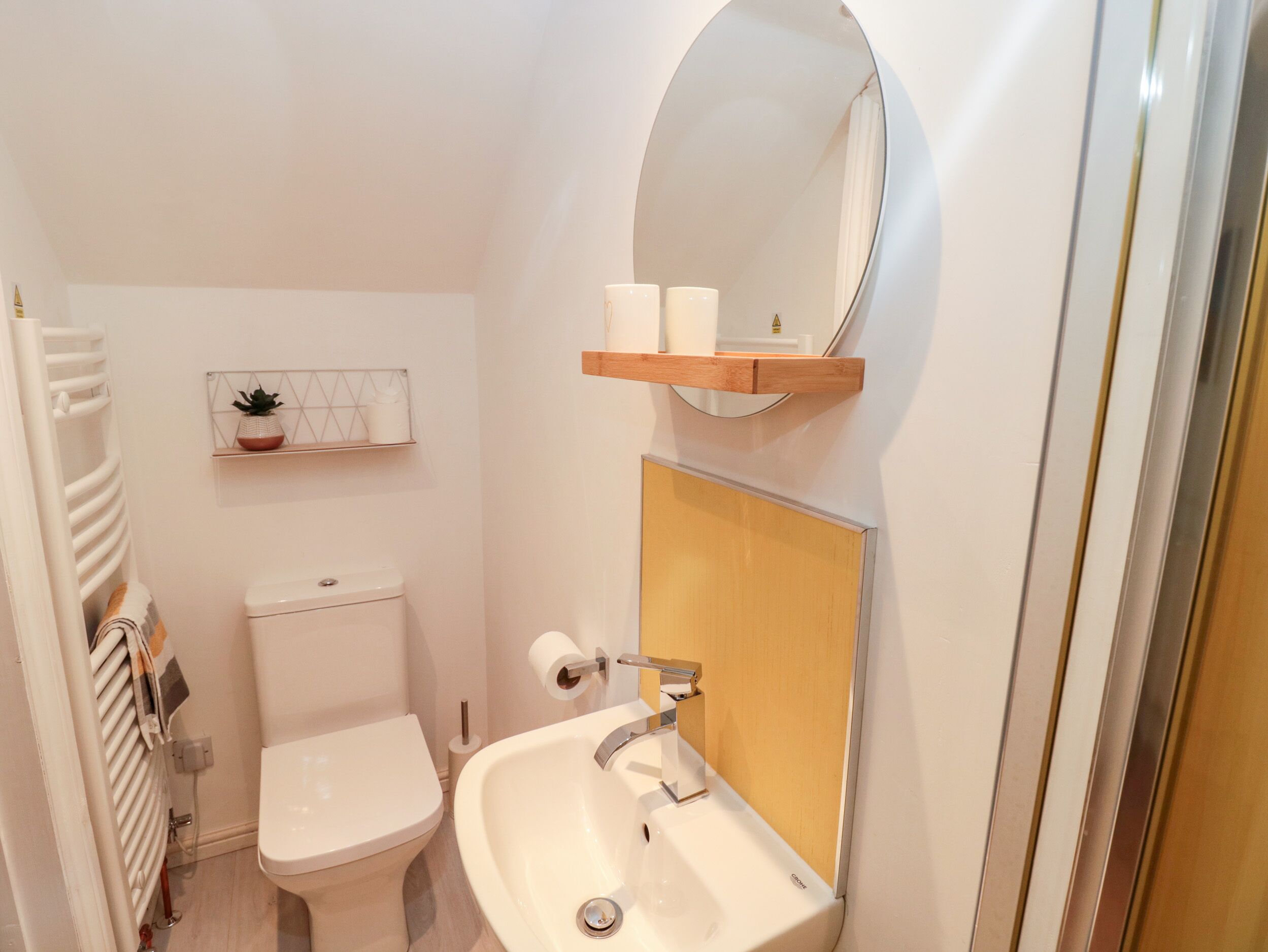 Un baño pequeño con inodoro, lavamanos y espejo sobre él.