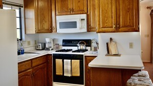 A kitchen with wooden cabinets, a white microwave, a stove, and a sink. - Horse Ranch Guest House above a barn Near Los Olivos for Families & Friends (Santa Ynez)