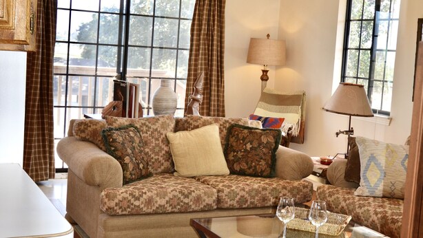 A cozy living room with a sofa, a glass coffee table, and a dining table. - Horse Ranch Guest House above a barn Near Los Olivos for Families & Friends (Santa Ynez)