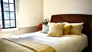 A neatly made bed with a white and beige blanket, two patterned pillows, and a small table with a lamp beside it. - Horse Ranch Guest House above a barn Near Los Olivos for Families & Friends (Santa Ynez)
