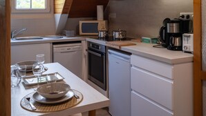 Une cuisine compacte équipée d’un four à micro-ondes, d’une cuisinière et d’une machine à café. Elle comprend également un évier et un lave-vaisselle.