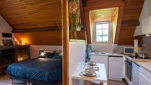 Une chambre confortable avec un lit, une petite table à manger et un coin cuisine équipé d’un évier et d’appareils électroménagers.